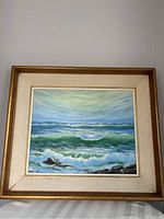 Framed oil painting showing the seascape with waves and rocks, centered in photo