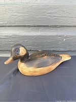 Side profile view showing the painted and carved wooden duck decoy with aged paint and wood grain.