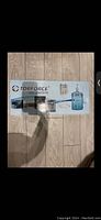 Box of TDR Force branded 5 gallon water dispenser pump system showing product image and branding on wood floor background.