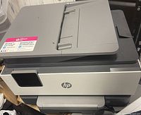 Front and top view of the HP OfficeJet Pro printer showing the scanner lid and output tray.