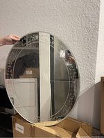 Front view of the round mirror showing the beveled edge and floral etched border.