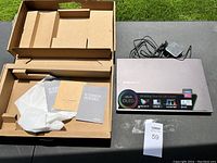 Open packaging showing laptop, power adapter, manuals and original box components.