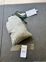 Packaged hammock in grey and black, compact in carry pouch with label taped underneath showing lot number.