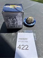 Photo of the commemorative ring next to its original box, showing packaging and logo details.