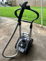 Full view of the Rowenta Precision Valet garment steamer showing the base, wheels, retractable handle, and flexible hose with ergonomic handle.