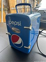 Front view of blue mini Pepsi cooler with vintage logo and chrome handles, showing compact size and sturdy handle on top