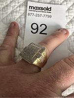 Men's large square ring shown on finger with clear cubic zirconia stones in gold-tone setting