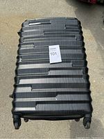 Front and top view of the black hard shell Samsonite suitcase showing the ribbed design and logo plate.