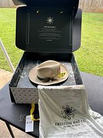 Fedora hat inside branded black box with instructions inside lid, showing packaging and lot presentation.
