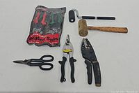 Photo of all six items: sealed Aviation Snips packaging with red and green handles, two pairs of black-handled metal shears, black paint roller, wooden mallet