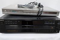 Sony 5 disc VHS exchanger stacked below silver DVD/CD player with cords on top of DVD player.