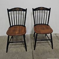 Pair of Hitchcock style chairs front view showing black frames, natural seats, and gilt decoration