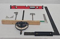 Photo showing all the measuring tools in the lot including level, radial saw measure, try square, table saw guide, steel scale, metal caliper, and metal angle tool.
