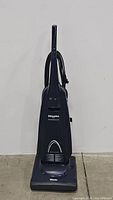 Front view of navy blue Miele s1761 Powerhouse upright vacuum cleaner showing the body, front base with Miele logo, and power cord wrapped on rear holders.