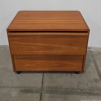 Front view of the modern teak filing cabinet showing two large drawers and warm wood finish.