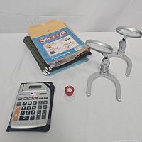 Full lot showing calculator, hanging folders, envelopes, magnifiers, and red tape