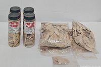 Four plastic containers and four plastic bags of used wooden plate joining biscuits for woodworking.