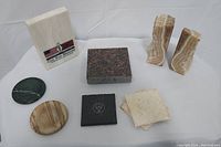 Photo of all stone items on a white background showing various bookends, coasters, and a granite slab.
