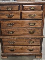 Front view of the oak tall chest showing all seven drawers closed with ornate brass handles.