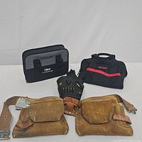 Three tool bags and one leather tool belt arranged on white background