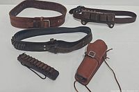 Photo showing all three leather belts and one leather holster together, highlighting varying styles and detailing.