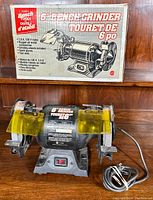 Bench grinder with original box, showing the motor specs and included accessories noted on the box