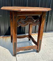 Side view of the antique Chinese hexagonal table showing leg inlay and carved wooden stretcher supports.