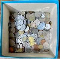 Blue and white box filled with assorted circulated coins of various countries and denominations.