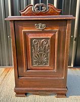 Front view of the Edwardian mahogany fireside coal cabinet showing the brass handle and carved panel on the door.