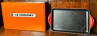 Le Creuset orange box with cherry red grill pan next to it