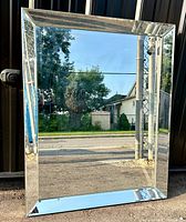 Front view of rectangular mirror with beveled glass and mirrored frame showing reflections of the outdoors.