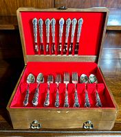 Full view of tarnish proof wooden chest with red felt lining containing the vintage silverplate flatware set including knives, forks, and spoons.