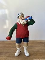 Full view of vintage biker Santa figurine standing on wooden surface with white background.