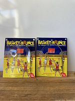Front view of two Basket Bounce vintage basketball games showing the colorful original boxes and game cases with the red hoops and player figures.
