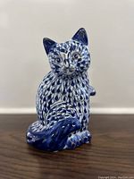 Front view of blue and white fishnet patterned cat figurine with gold accents on ears, paws, and face.