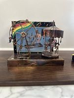 Copper carousel music box with spinning ferris wheel shown from front angle with box in background.