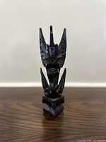 Front view of a dark wood carved Vishnu statue with detailed patterns and stylized facial features.