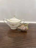 Photo showing the Lenox sugar dish and jeweled bird figurine side by side on a wooden surface.
