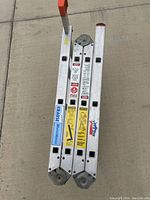 Top view of folded Krause MultiMatic aluminum ladder with stickers and caution labels visible.
