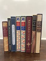 Front spines and titles of 8 vintage hardcover books arranged vertically on a shelf.