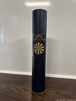 Black cylindrical container with label showing 'Saf-T-Fit Magnetic Dart Board' and image of the dart board.