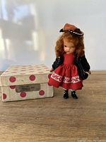 Nancy Ann Storybook doll standing next to the original shoe box on a wooden surface.