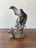 Front view showing the face of a Native American Indian with an eagle spreading wings above and a wolf howling beside the base.