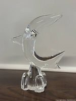 Multiple angles showing clear crystal shark figurine with water splash base on wooden surface