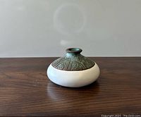 Front and side view of the round pottery vase showing textured dark green upper and smooth white lower body.