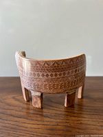 Front view of the wooden lion art piece showing intricate geometric carvings and four supporting legs.