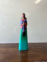 Front view of vintage Mexican pottery figurine showing a woman in traditional dress with hands clasped and turquoise skirt.
