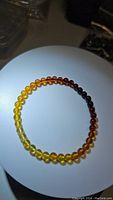 Top-down photo of a stretchy Baltic amber bead bracelet showing gradient colors from light yellow to dark reddish amber.
