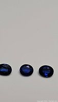 Three oval-cut royal blue sapphires on white background