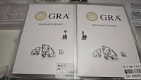 Front view of two GRA moissanite reports with earrings presented on top showcasing certification and stones.